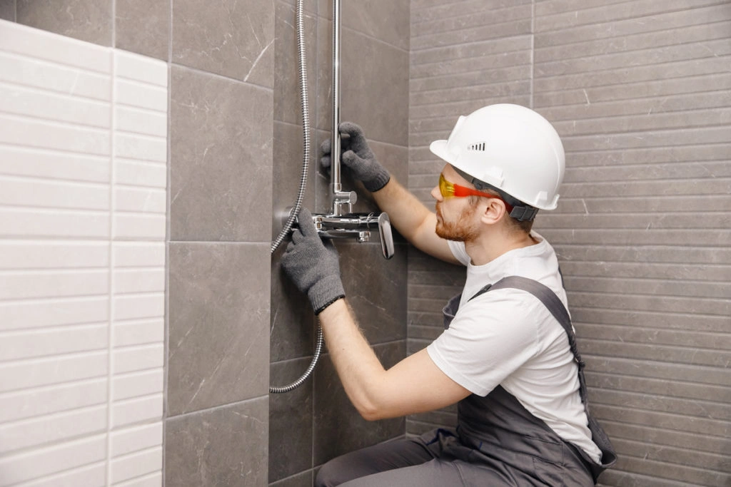 Plombier posant une cabine de douche à l’italienne dans une salle de bain moderne
