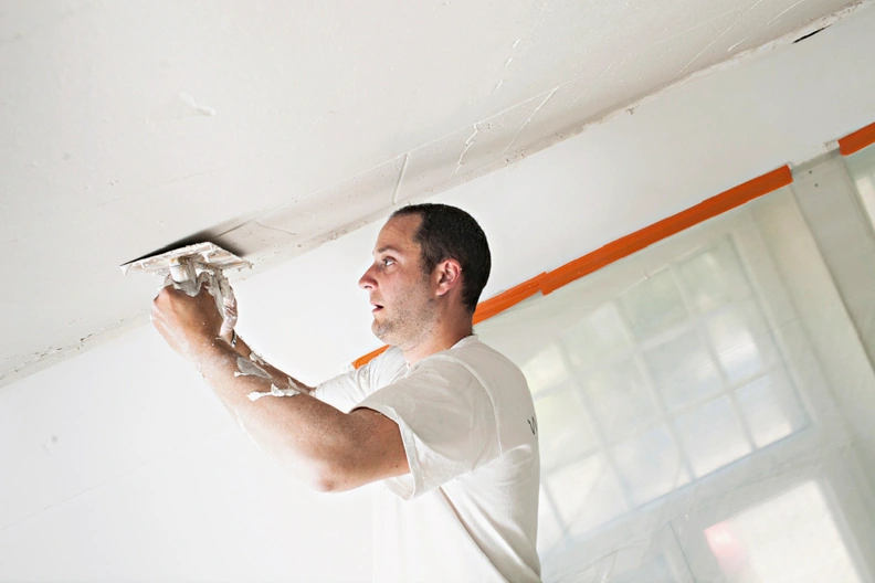 Peintre plâtrier appliquant de l’enduit sur un mur avant peinture.
